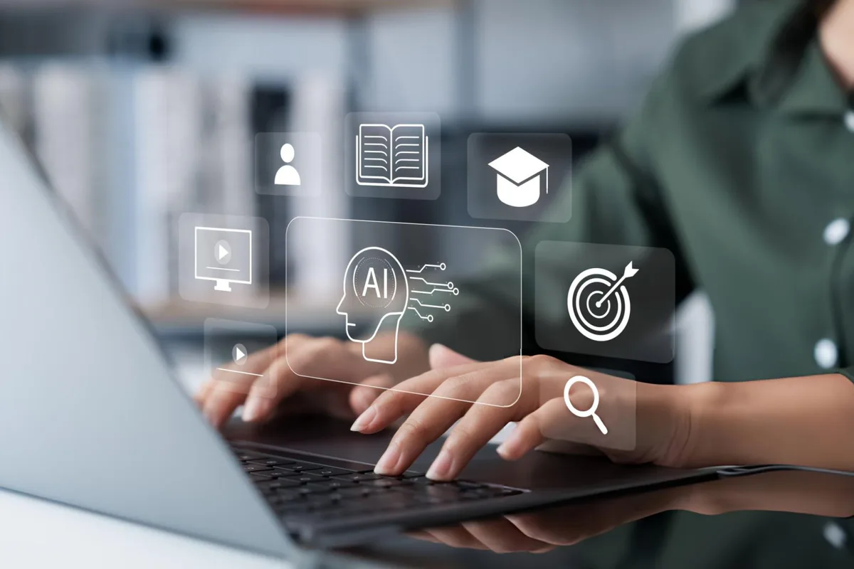Hands typing on a laptop with AI, learning and career icons floating above the keyboard