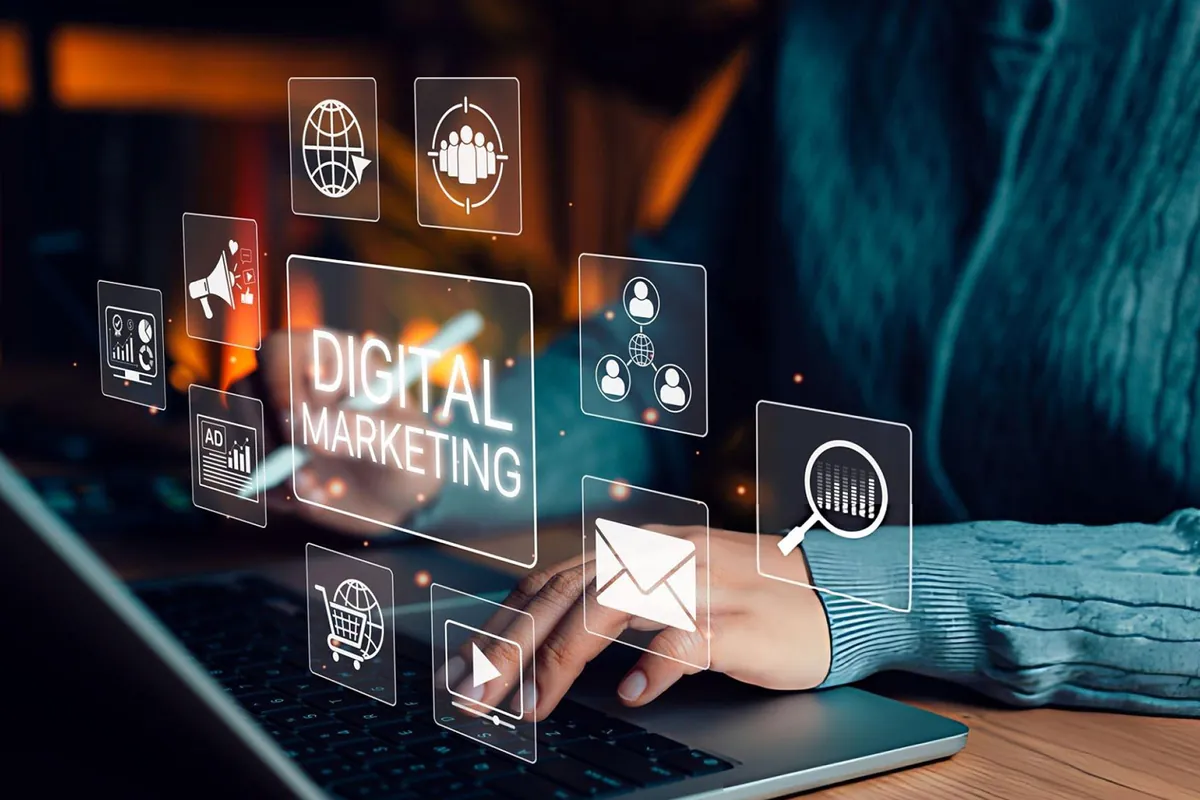 A person working on a laptop with digital marketing icons floating above the keyboard